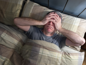 homem acordando cansado com dor de cabeça, ilustrando a relação entre sono ruim e dores persistentes